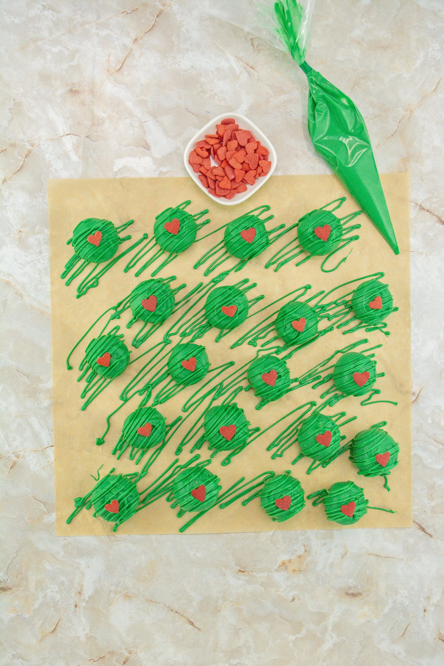 grinch truffles arranged in rows on a sheet of brown parchment paper