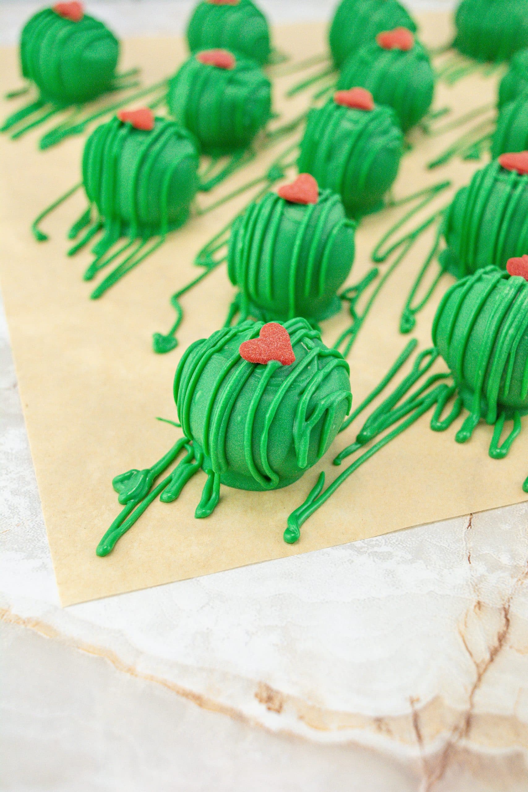 grinch truffles arranged in rows on a sheet of brown parchment paper