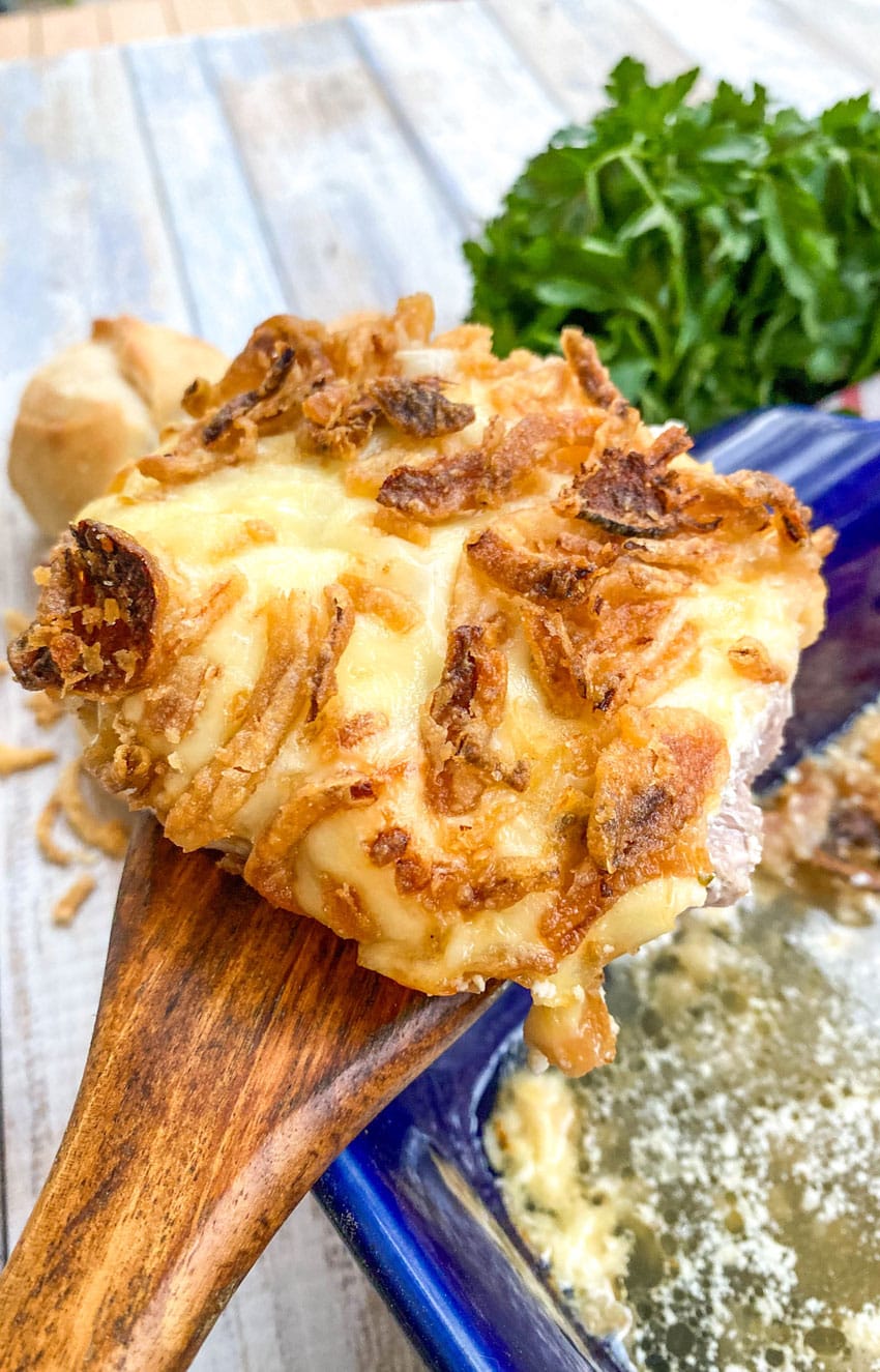 a wooden spatula holding up a french onion pork chop