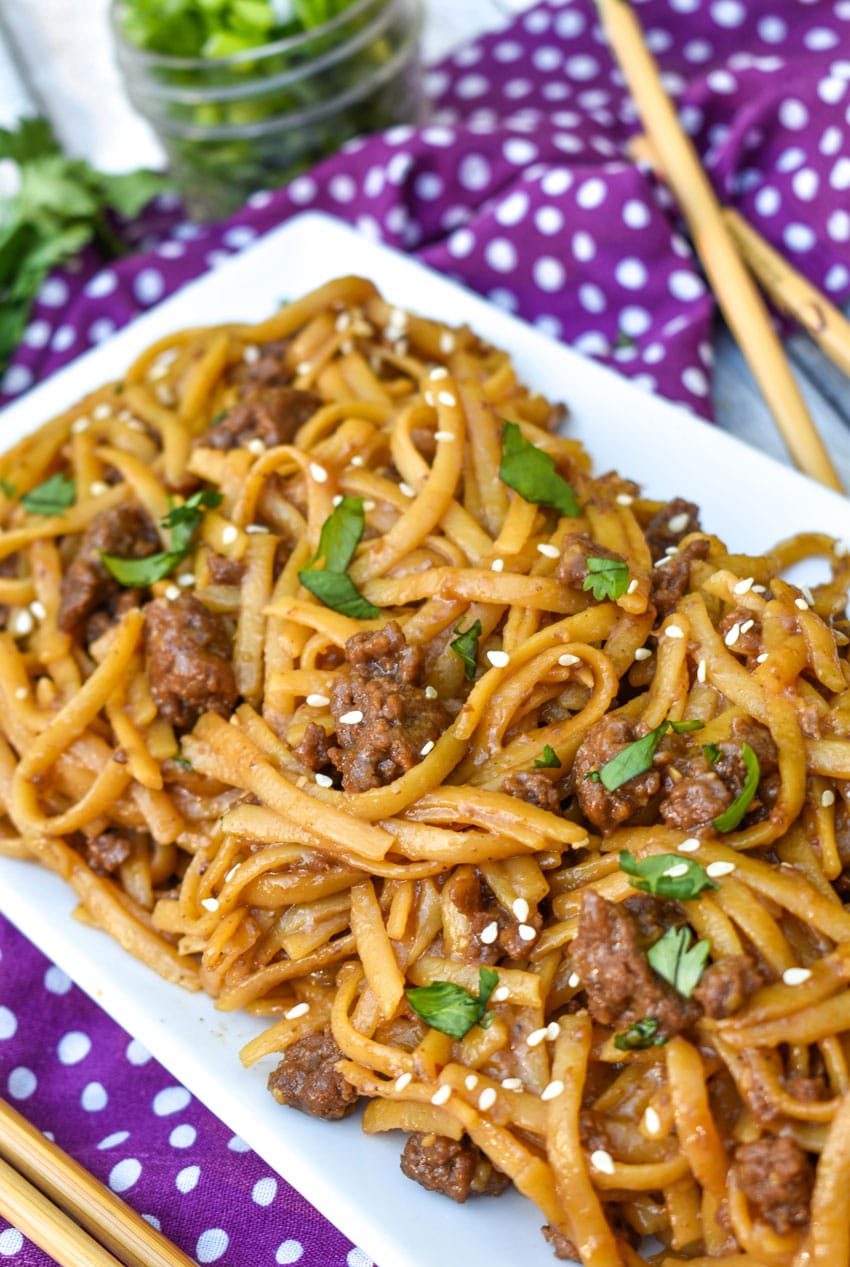 easy mongolian ground beef and noodles on a white platter with wooden chop sticks on the side