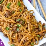easy mongolian ground beef and noodles on a white platter with wooden chop sticks on the side