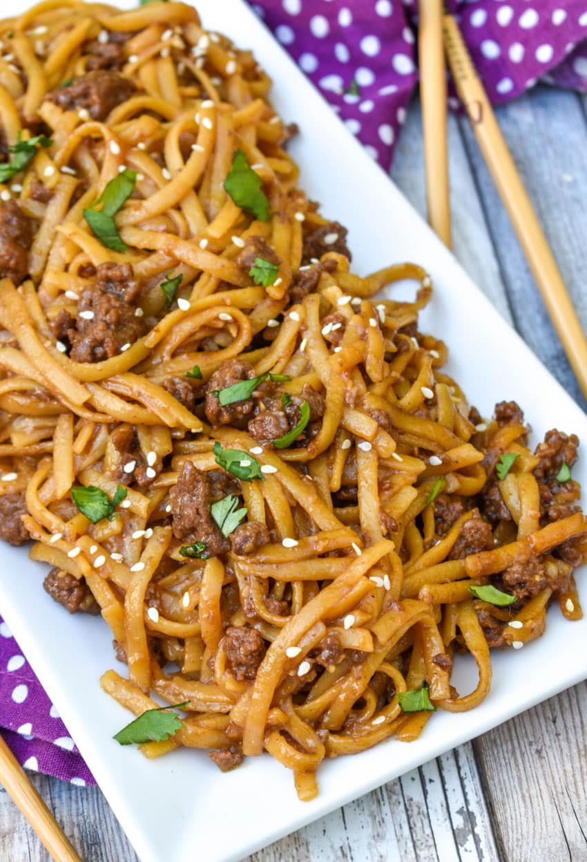 easy mongolian ground beef and noodles on a white platter with wooden chop sticks on the side