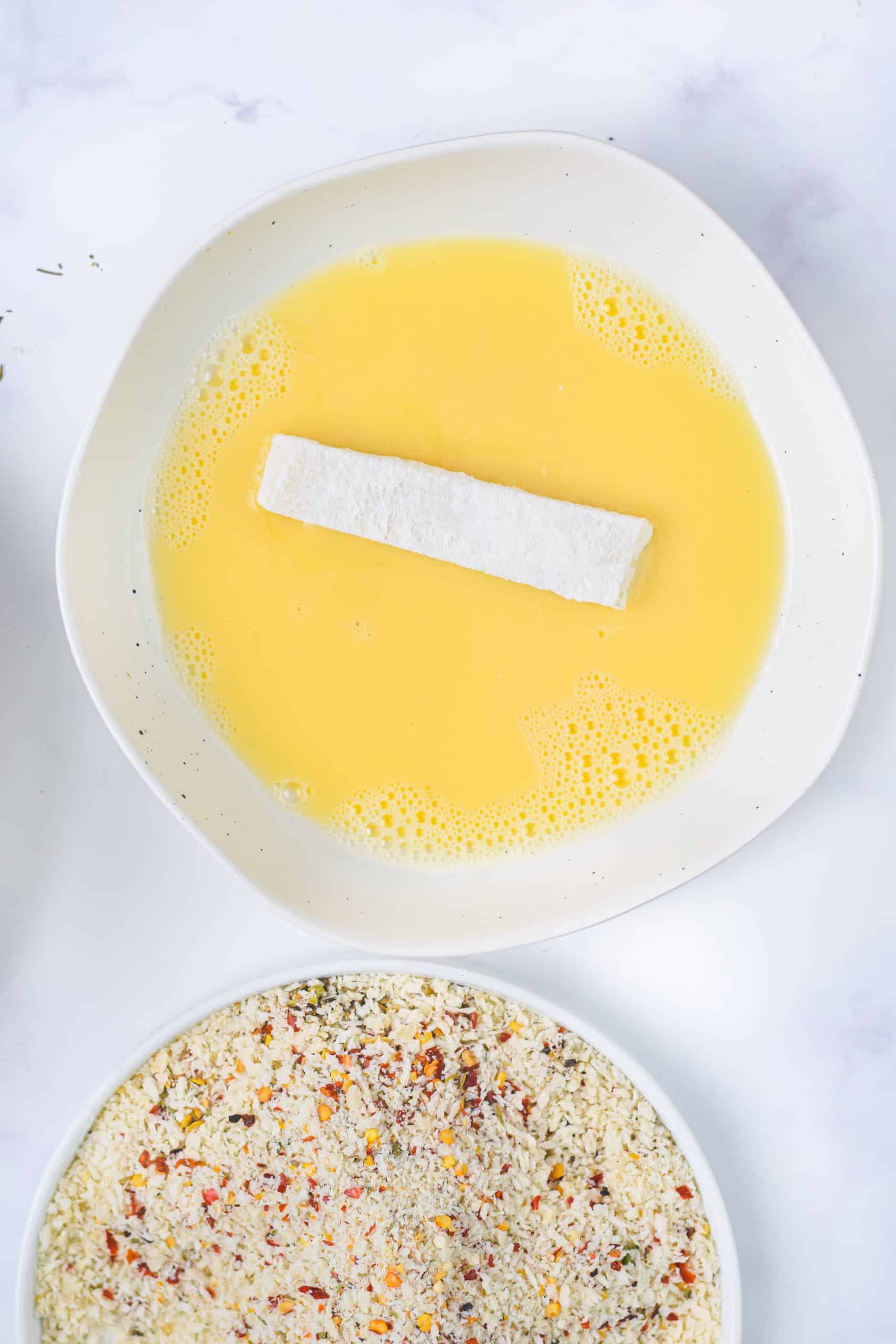 a piece of mozzarella cheese coated in egg on a white plate
