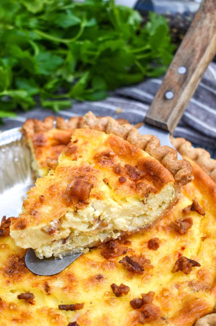 a wooden spatula holding a slice of bacon swiss quiche
