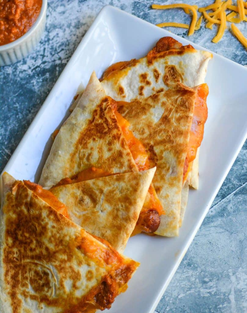 slices of chili cheese dog quesadillas on a white serving platter