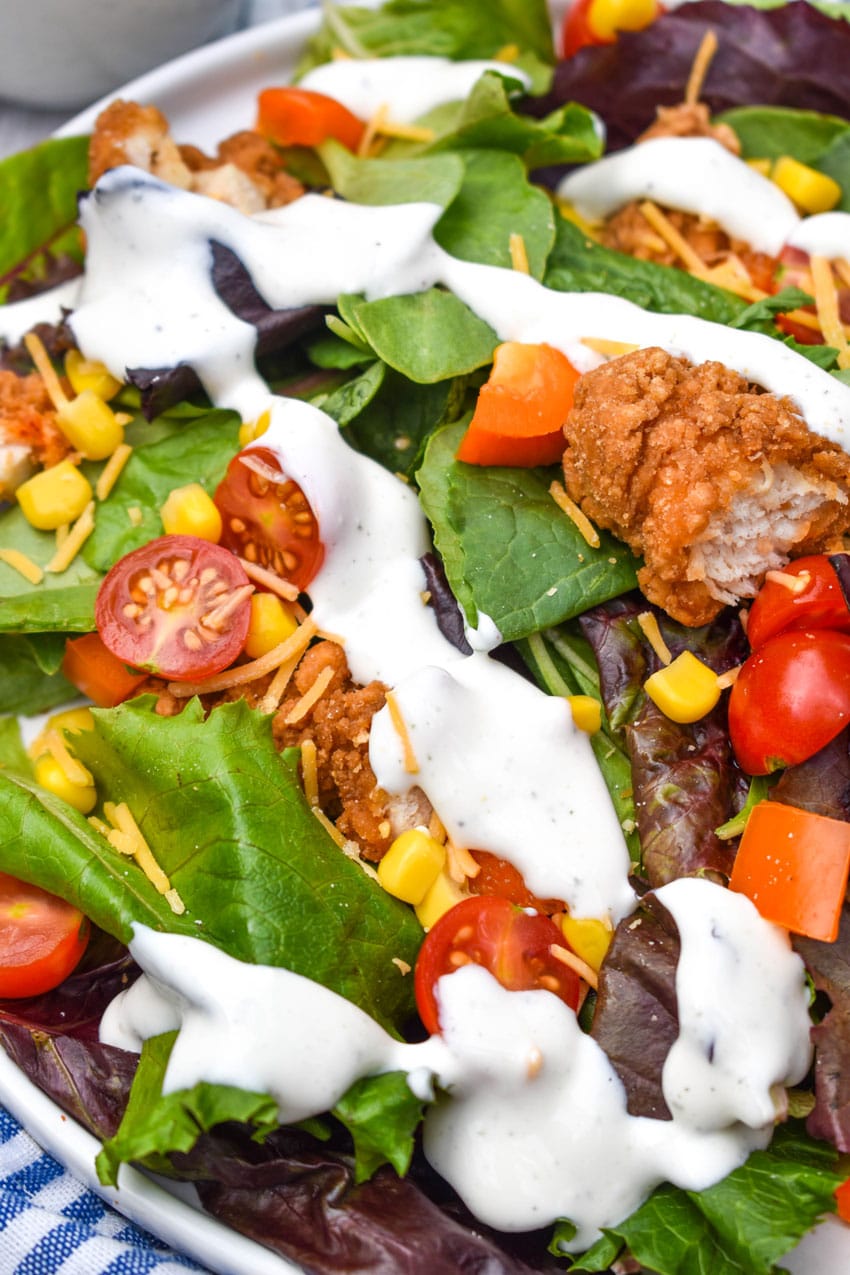 cottage cheese ranch dressing drizzled over a fresh garden salad on a white plate