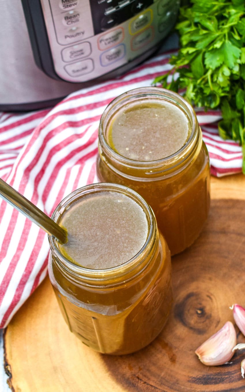 a spoon stuck in a glass jar filled with instant pot chicken broth
