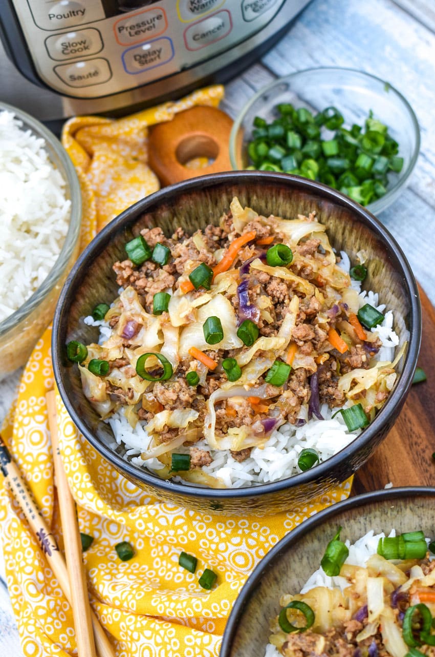 instant pot egg roll in a bowl sitting on a wooden cutting board with chop sticks on the side