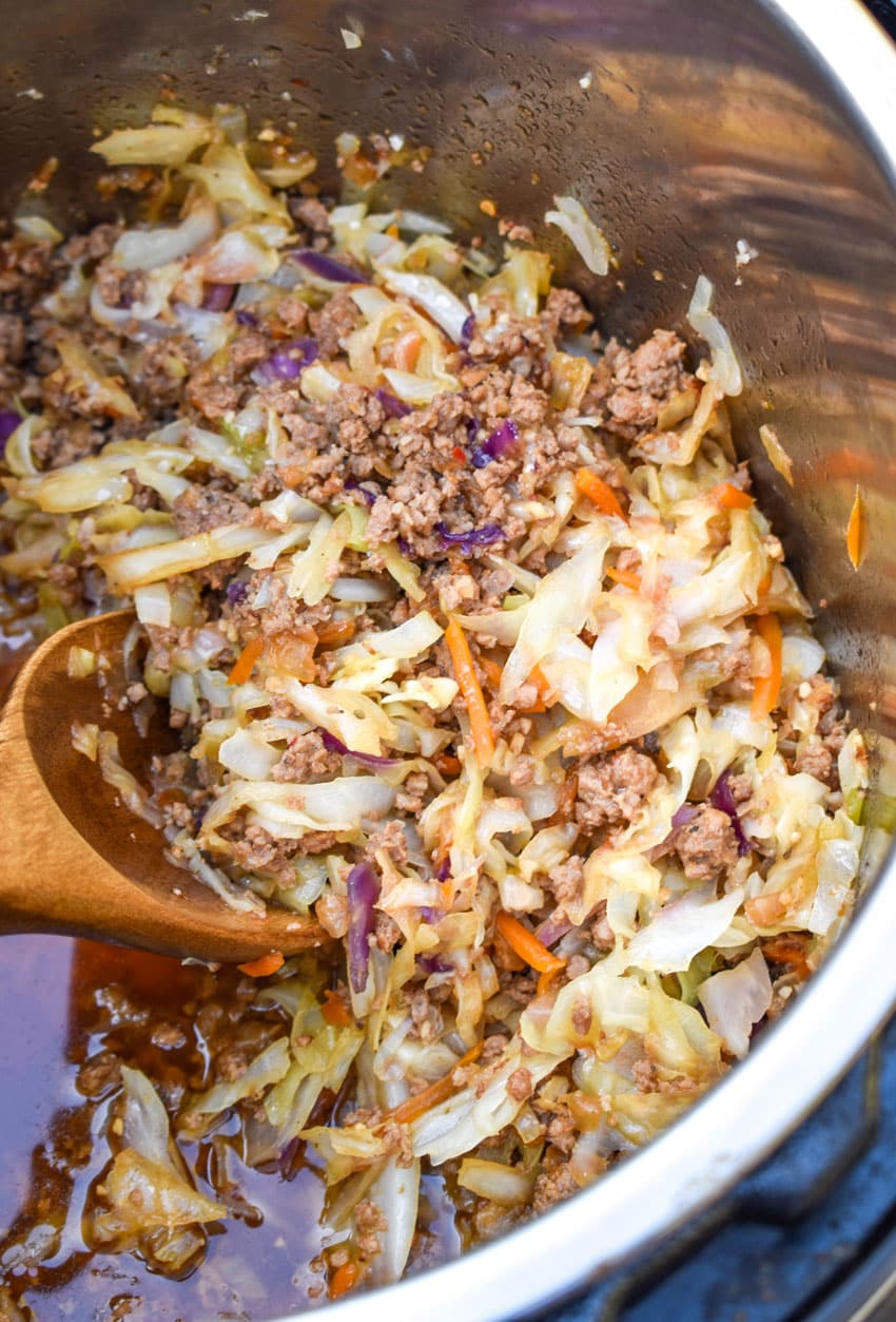egg roll in a bowl filling in an instant pot with a wooden spoon on the side