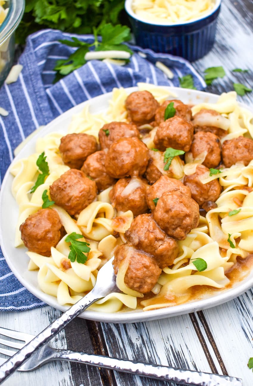 instant pot french onion meatballs over egg noodles on a white plate