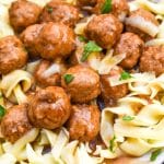 instant pot french onion meatballs over egg noodles on a white plate