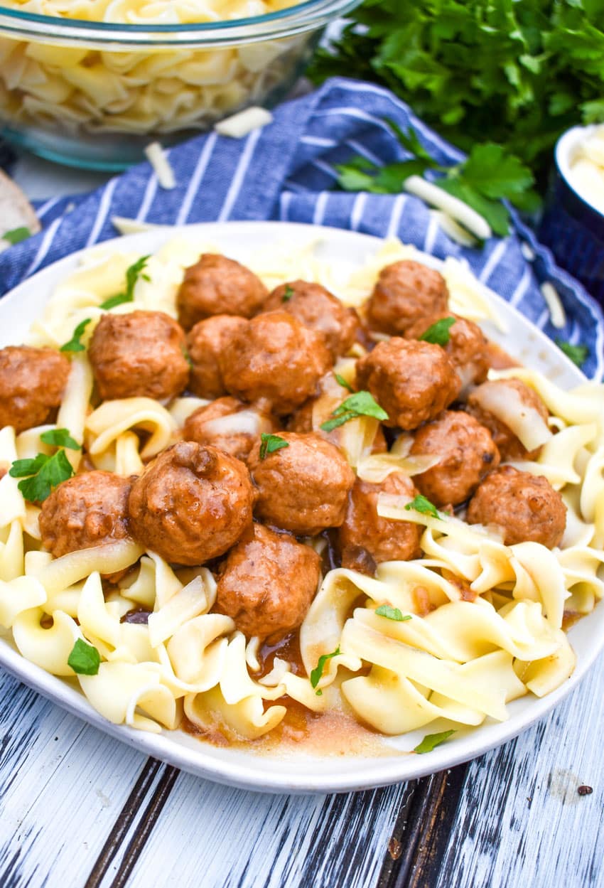 instant pot french onion meatballs over egg noodles on a white plate