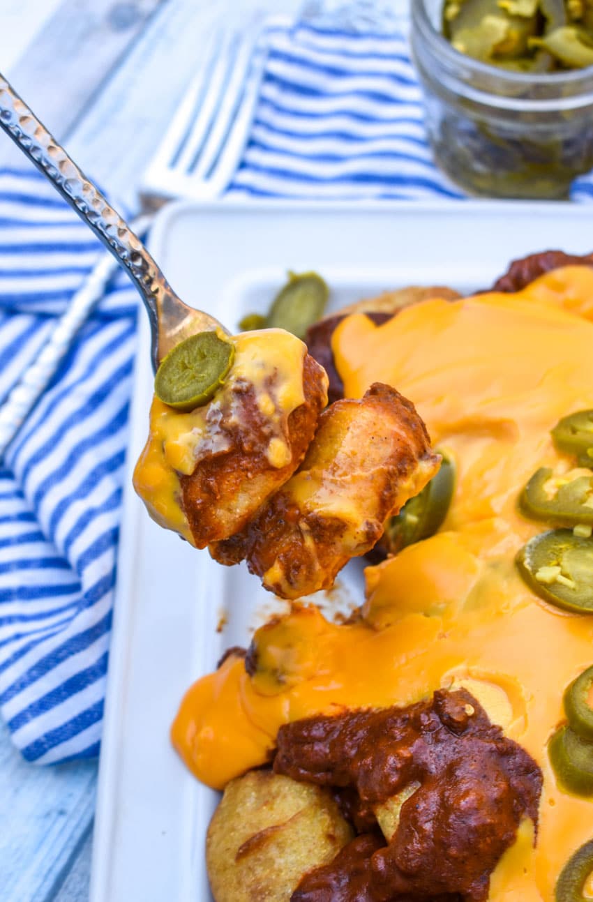 a silver fork holding up a scoop of chili cheese corn dog nachos