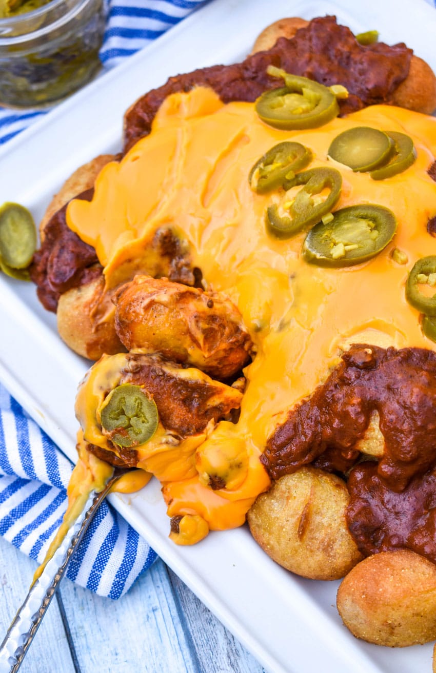 a fork scooping corn dog nugget nachos off of a white platter