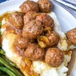 slow cooker Mississippi meatballs over mashed potatoes on a white plate