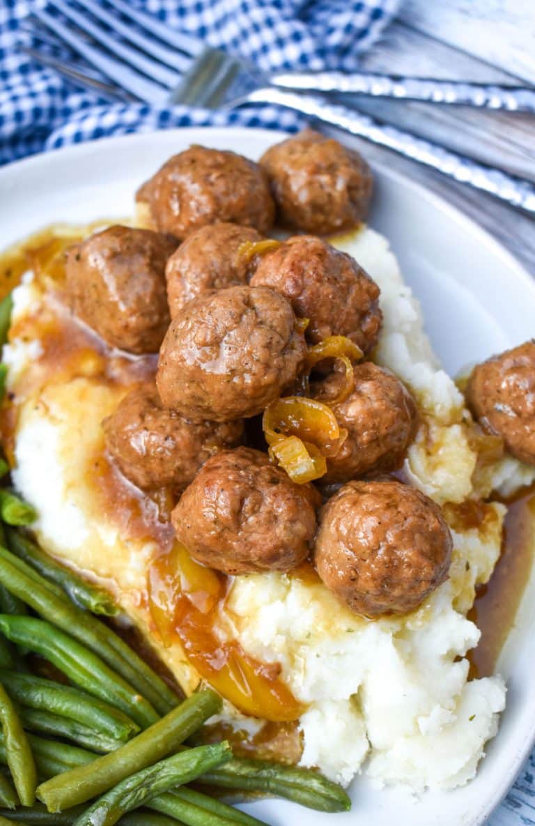 slow cooker Mississippi meatballs over mashed potatoes on a white plate