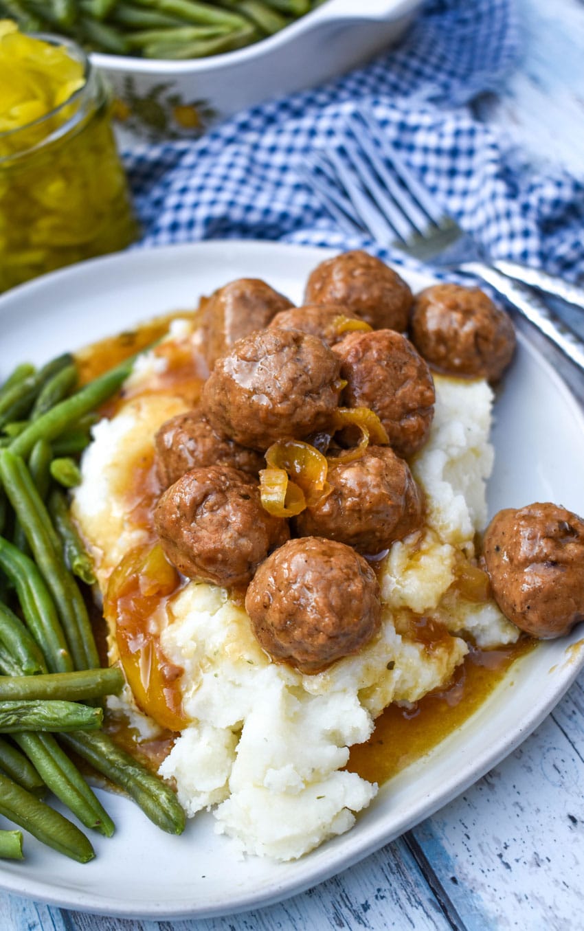 slow cooker Mississippi meatballs over mashed potatoes on a white plate