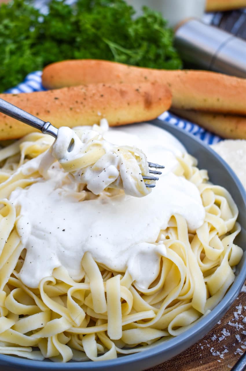 homemade alfredo sauce and noodles wrapped around the tines of a silver fork