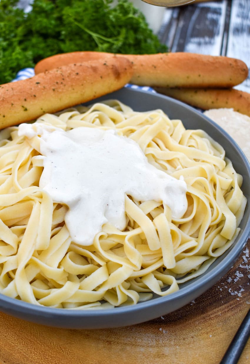easy homemade alfredo sauce served over cooked fettuccini noodles in a gray bowl