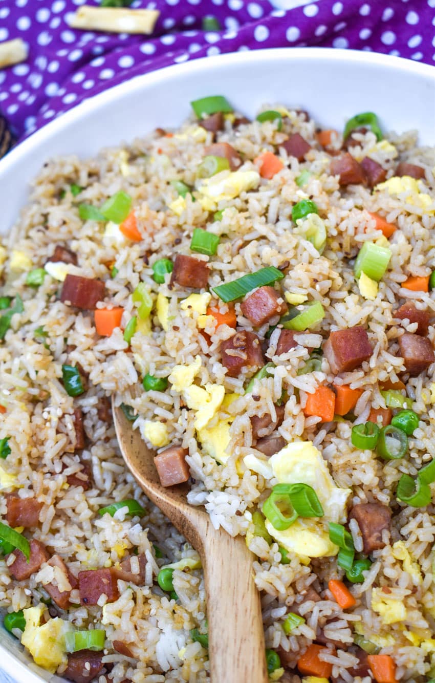 a wooden spoon stuck in a bowl of spam fried rice