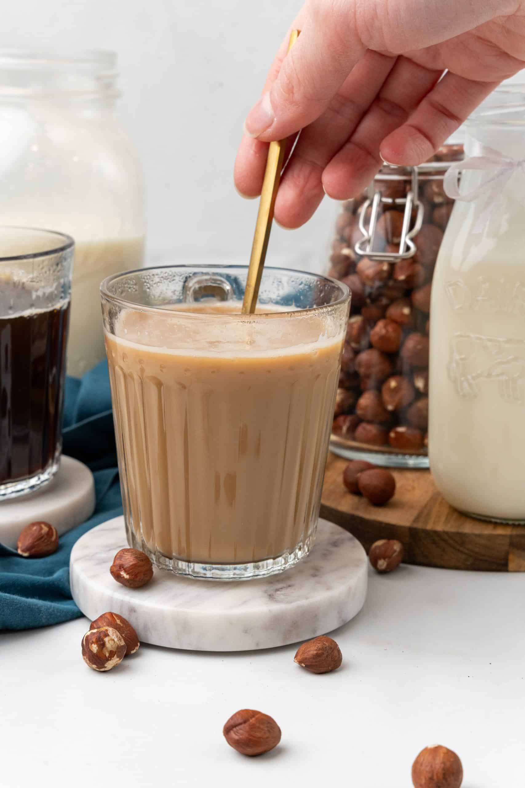 a gold spoon stirring coffee and homemade creamer together in a glass mug