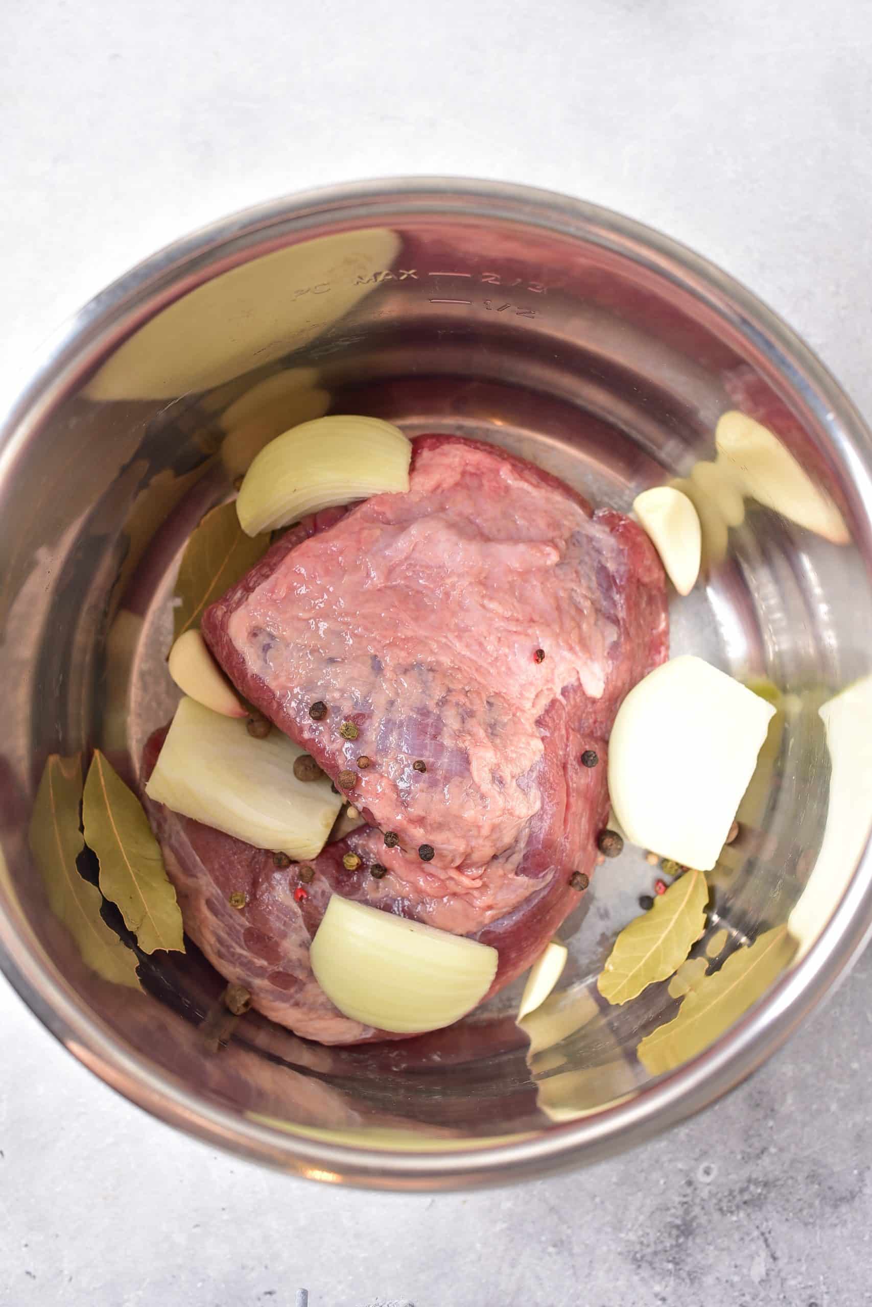corned beef brisket and onions in the bowl of an instant pot