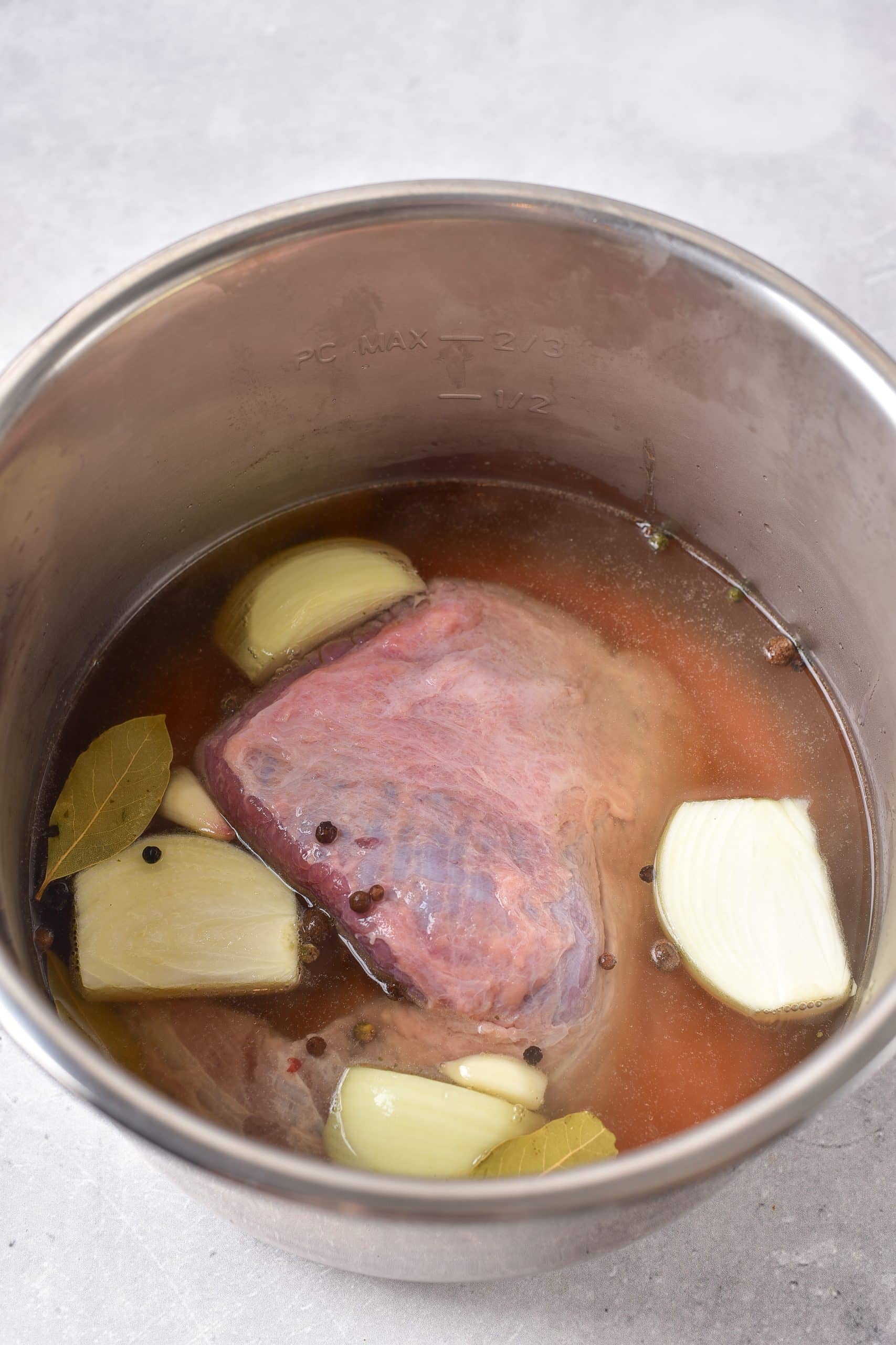 corned beef brisket and onions in broth in the bowl of an instant pot