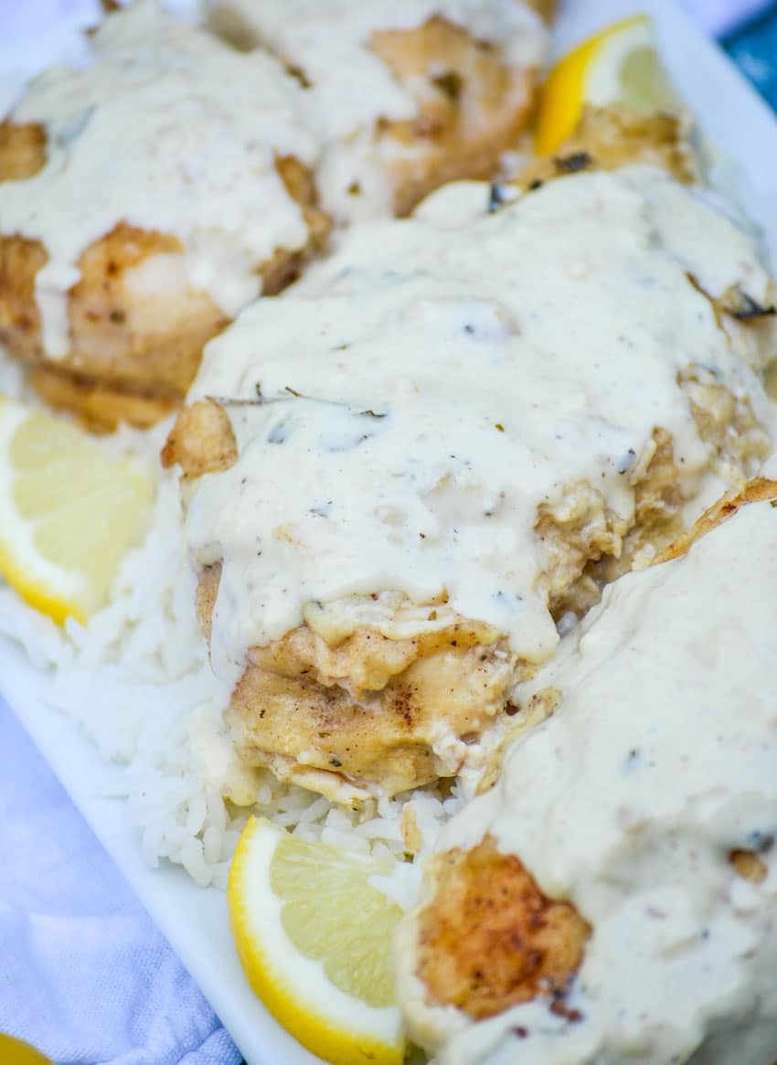 creamy lemon over a bed of steamed white rice on a white platter with lemon slices on the side