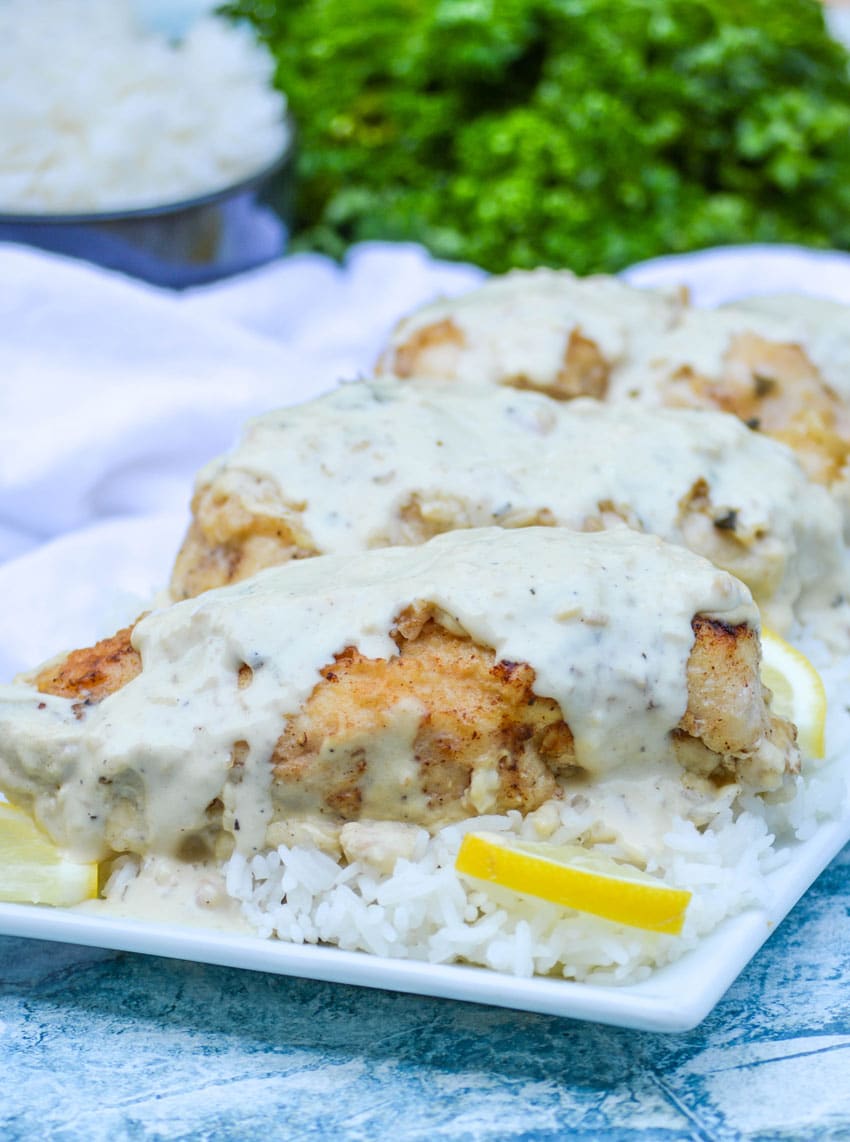 creamy lemon over a bed of steamed white rice on a white platter with lemon slices on the side