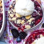 sugar cookie berry cobbler in gray bowls topped with scoops of vanilla ice cream