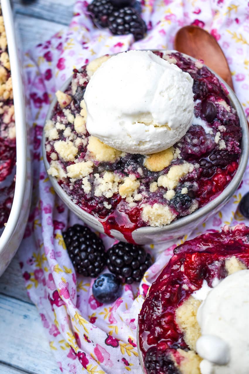 sugar cookie berry cobbler in gray bowls topped with scoops of vanilla ice cream