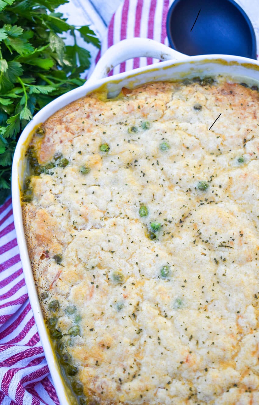 easy chicken cobbler with vegetables in a white casserole dish