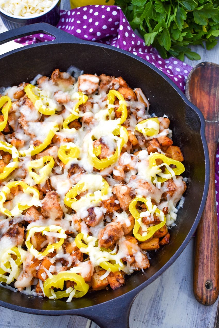 mississippi chicken and potato skillet recipe topped with melted cheese and pepperoncini slices in a cast iron skillet