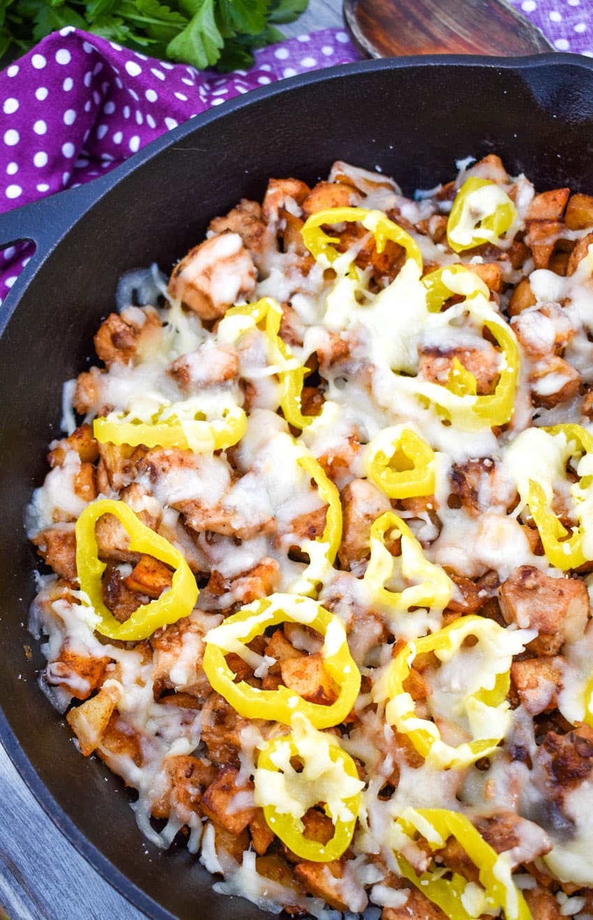 mississippi chicken and potato skillet recipe topped with melted cheese and pepperoncini slices in a cast iron skillet