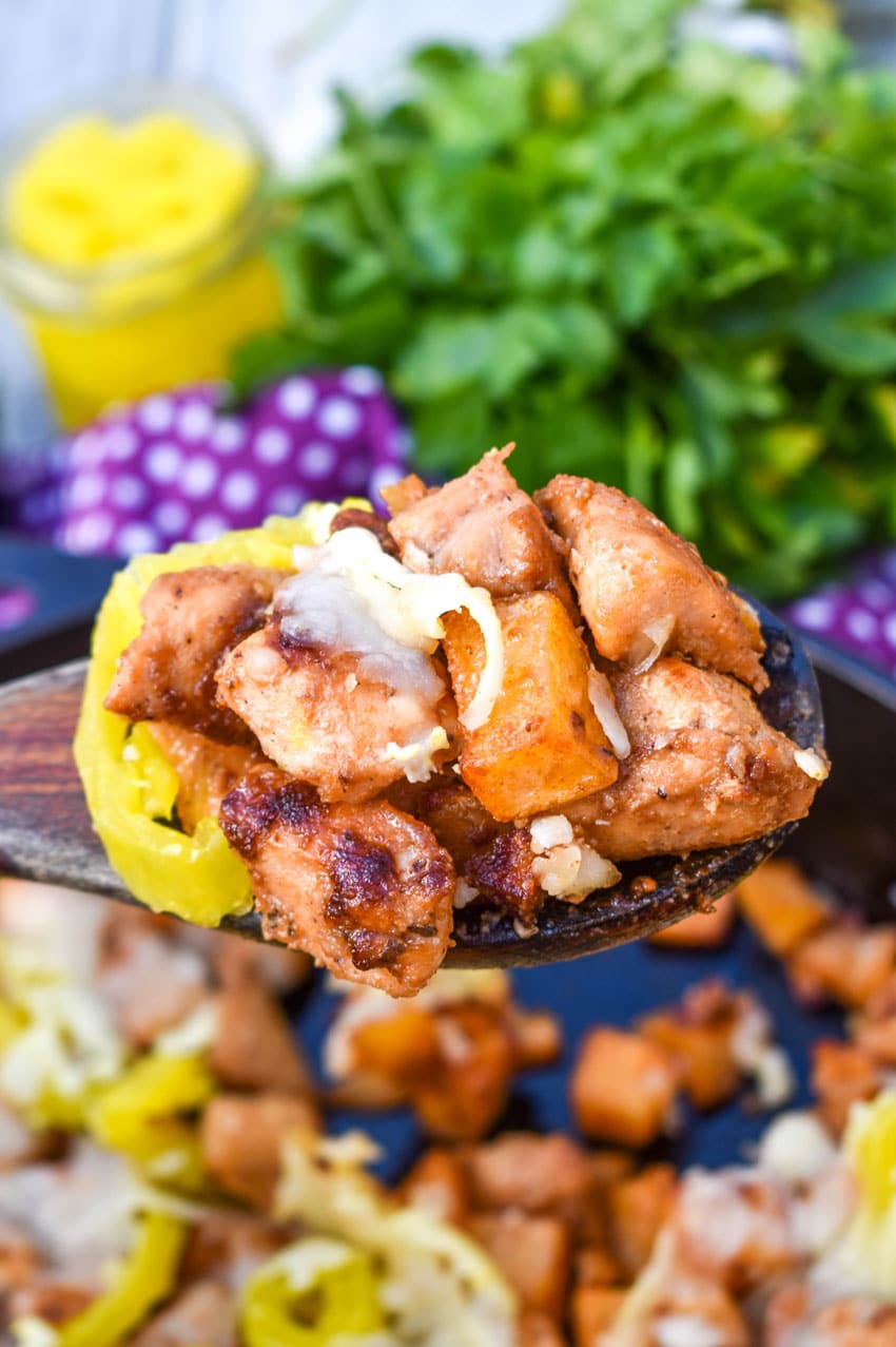 a wooden serving spoon holding up a scoop of mississippi chicken and potatoes