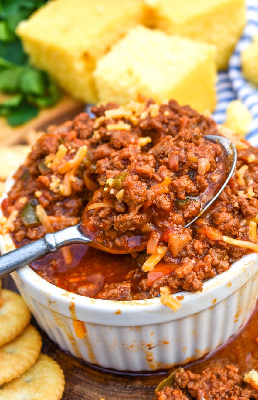 a silver spoon resting on a white bowl filled with chili without beans
