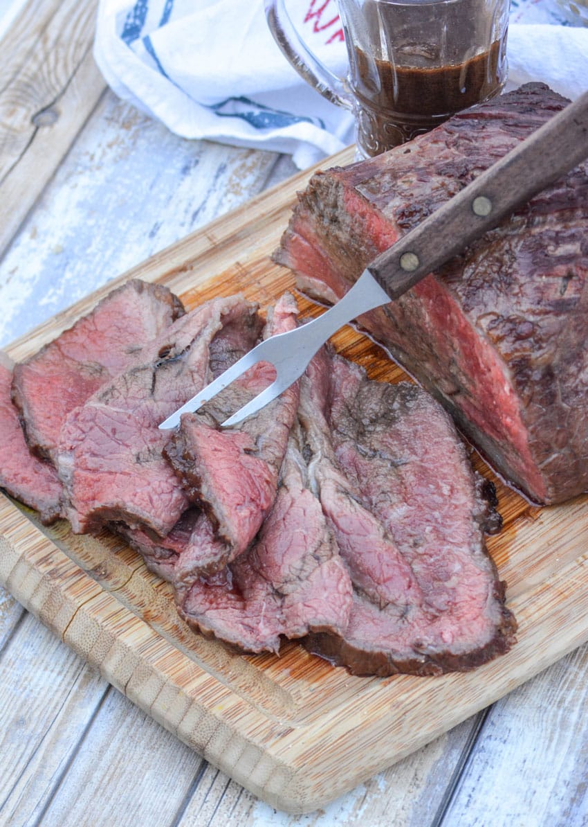slices of worcestershire marinaded bottom round roast on a wooden cutting board