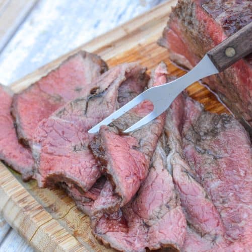 slices of worcestershire marinaded bottom round roast on a wooden cutting board