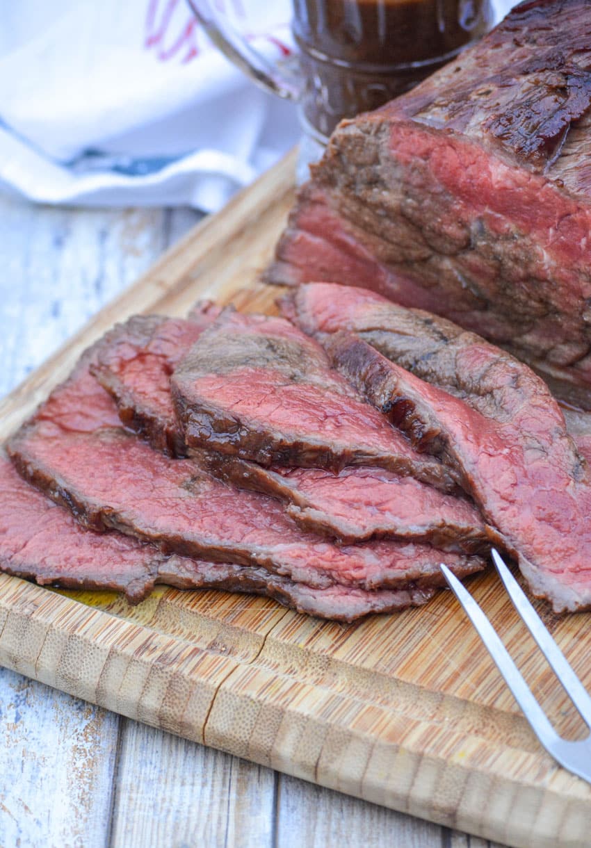 slices of worcestershire marinaded bottom round roast on a wooden cutting board