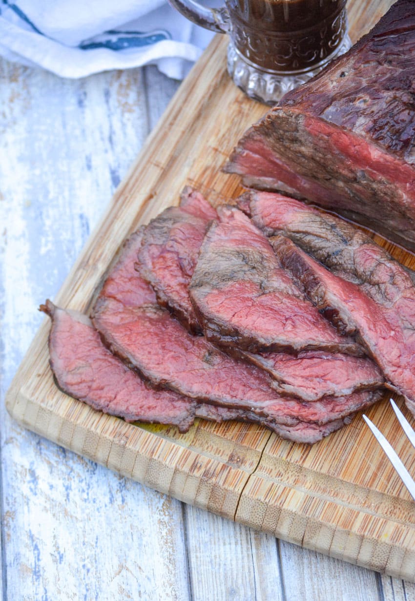slices of worcestershire marinaded bottom round roast on a wooden cutting board