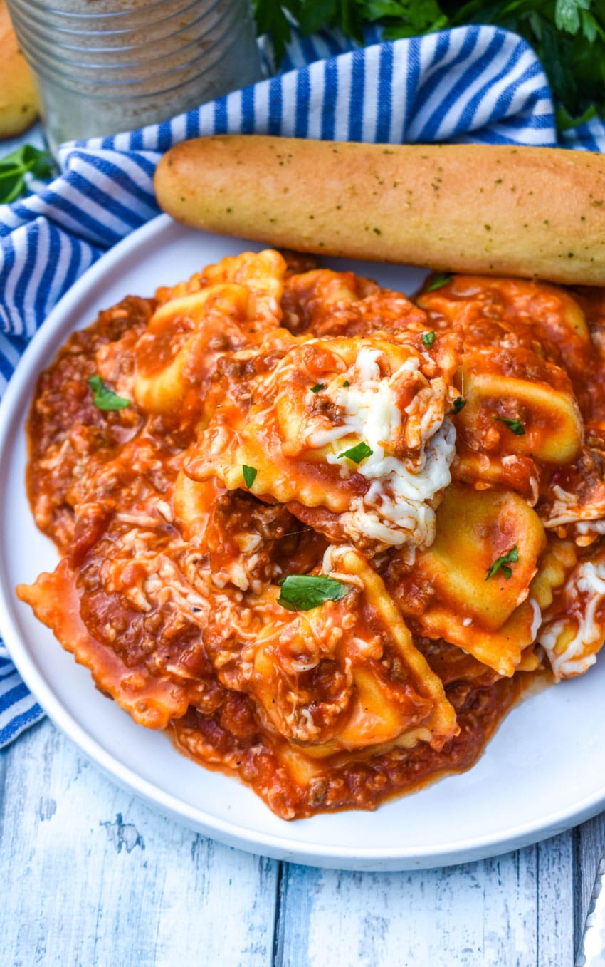 skillet ravioli lasagna on a white plate with a bread stick on the side