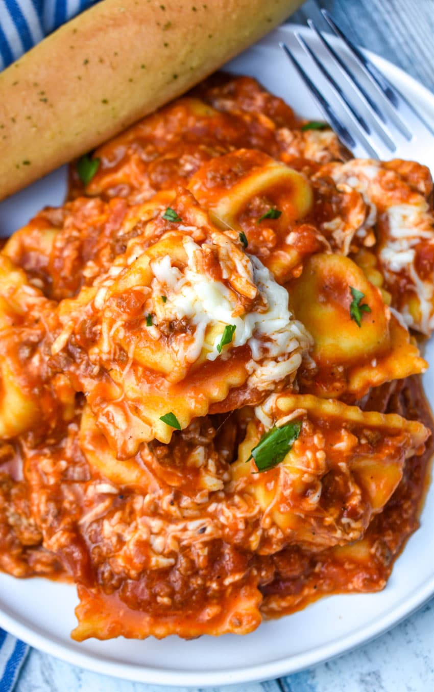 skillet ravioli lasagna on a white plate with a bread stick on the side
