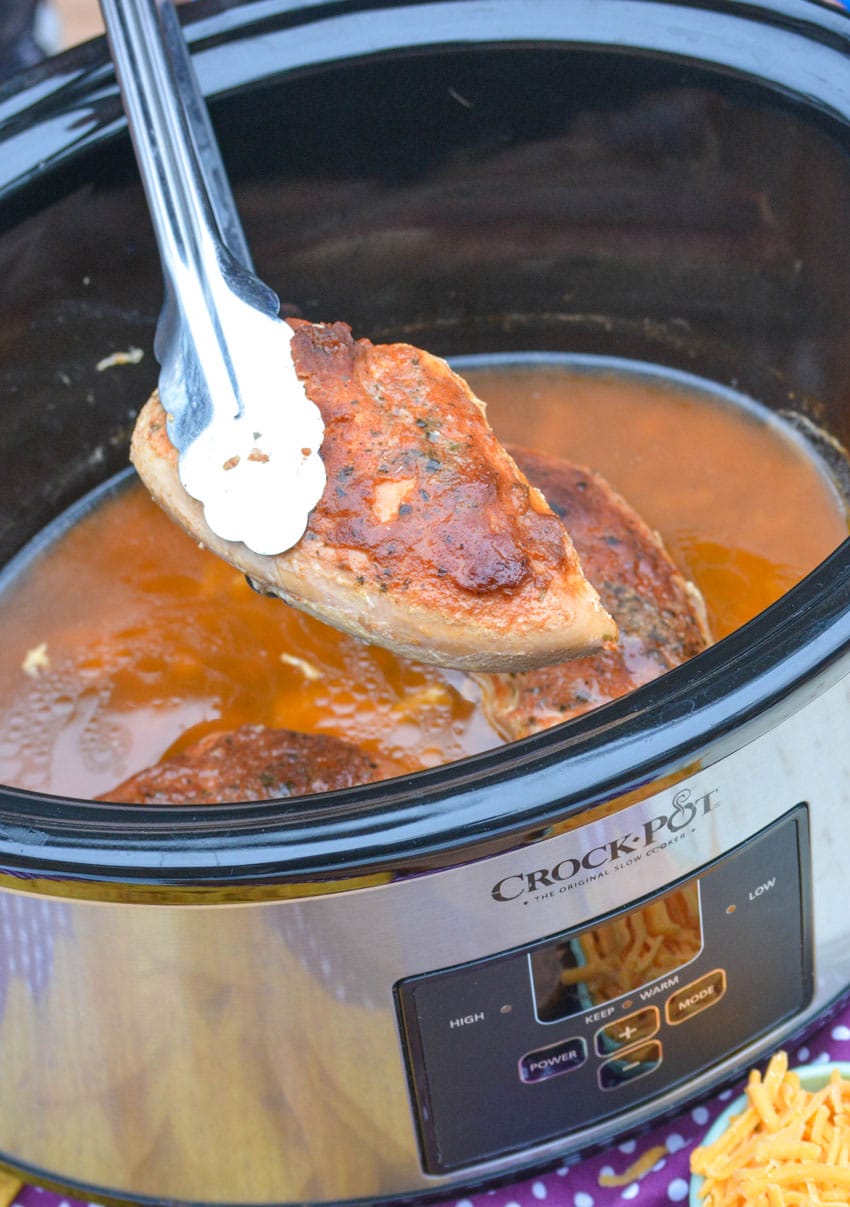 silver tongs holding up a piece of slow cooker cool ranch chicken