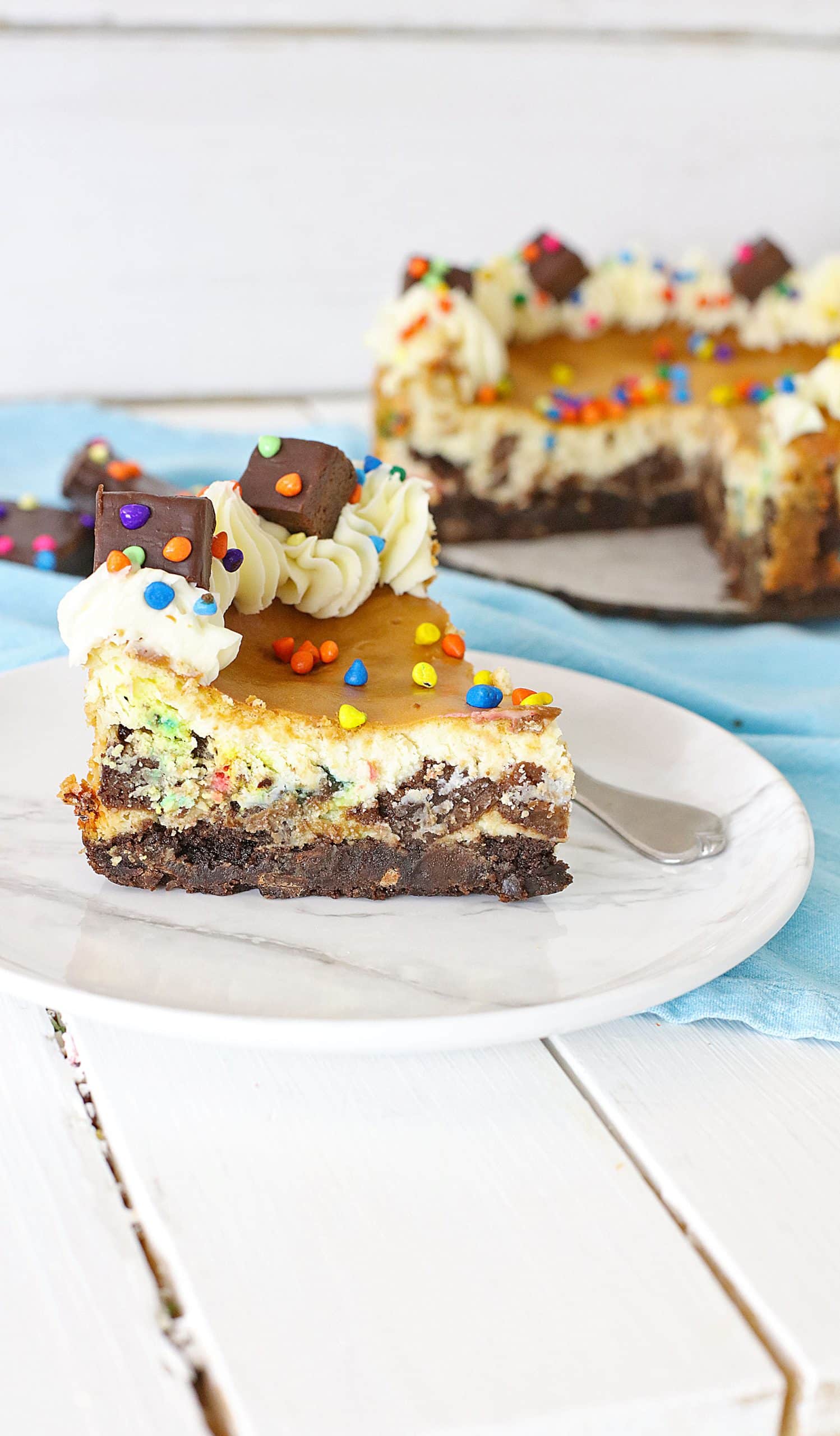 a slice of cosmic brownie cheesecake on a small white plate