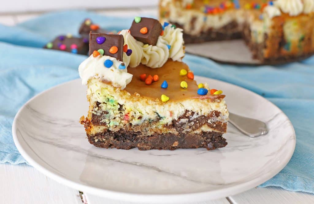a slice of cosmic brownie cheesecake on a white plate