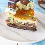 a slice of cosmic brownie cheesecake on a white plate