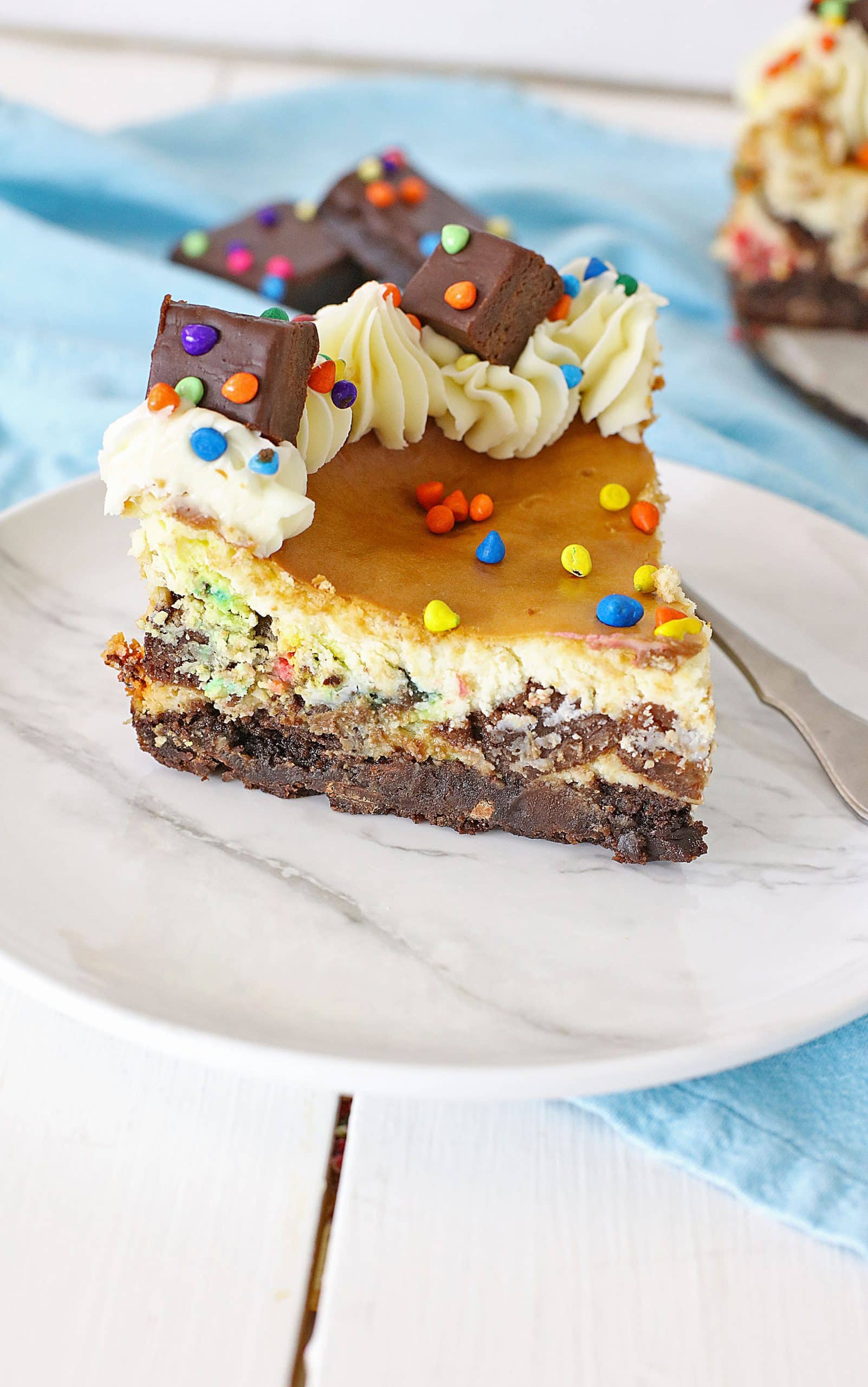 a slice of cosmic brownie cheesecake on a white plate
