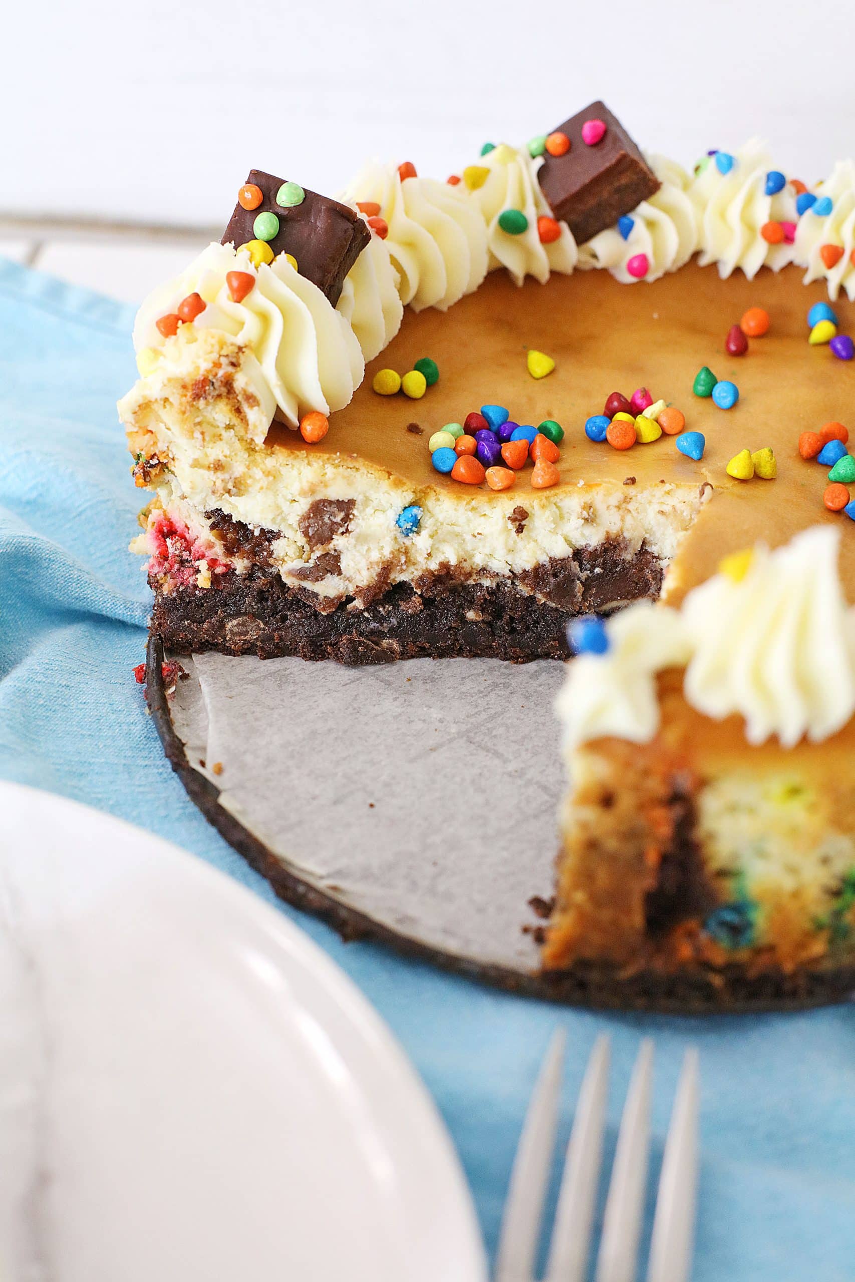 a cosmic brownie cheesecake with a slice removed to reveal the inner layers
