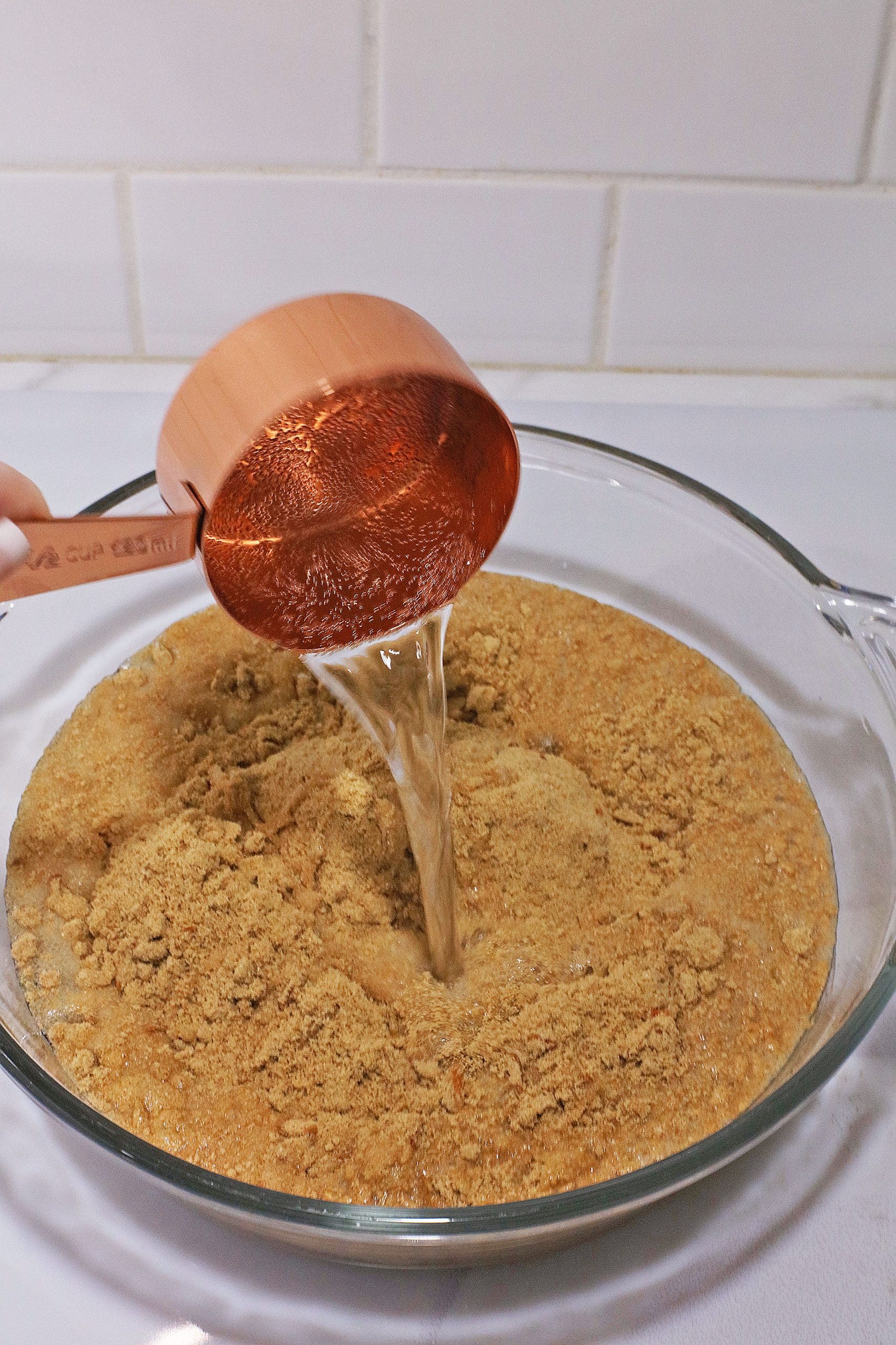cream soda being poured into carrot cake mix in a glass mixing bowl
