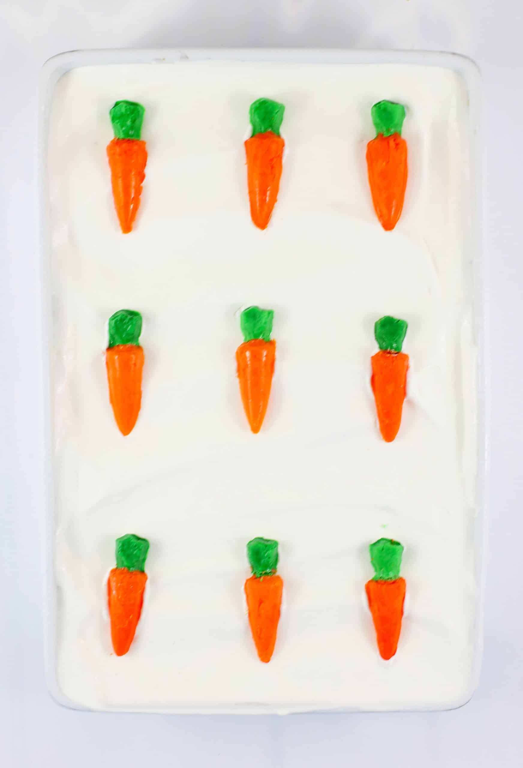 candy chocolate carrots in three rows on top of a carrot cake ice cream cake